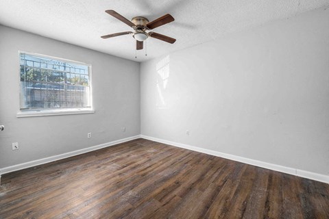 an empty living room with wood floors and a ceiling fan